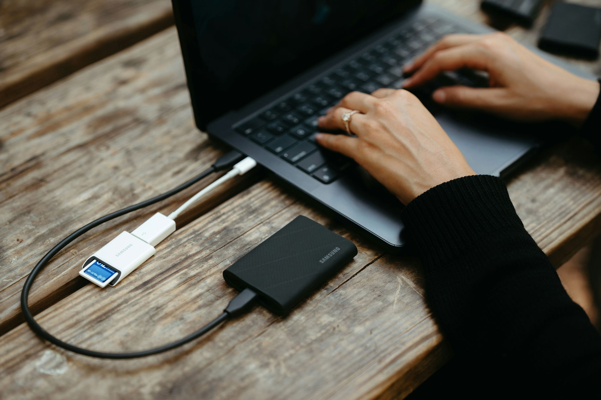 Hands typing on laptop connected to external hard drive.